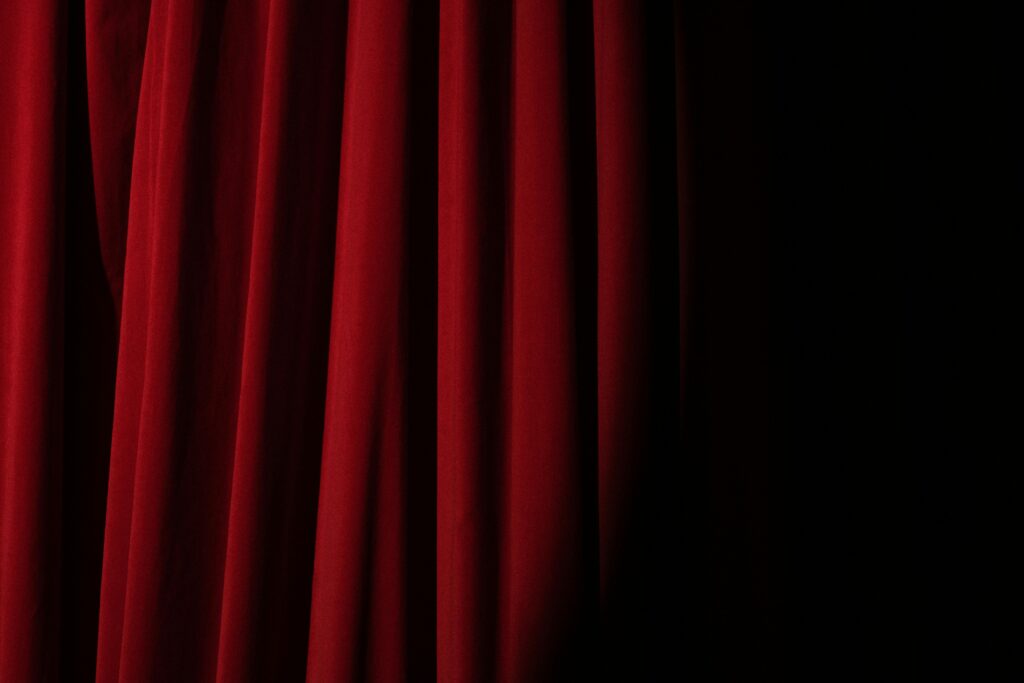 Elegant red velvet curtain with dramatic lighting perfect for theater themes.